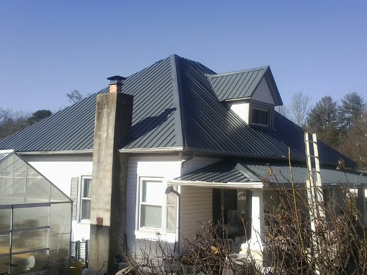 Dark blue standing seam metal roof on a white farmhouse with dormer — Slate & Tile Roof Repair by Roofing Brothers in Dedham