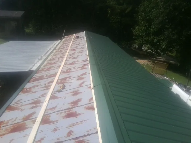 Old rusted panels beside newly installed green metal roofing — Wind Damage Roof Repair by Roofing Brothers in Dedham