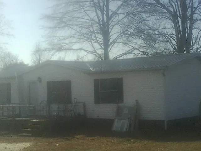 New metal roof on a white painted brick home on a foggy morning in Dedham