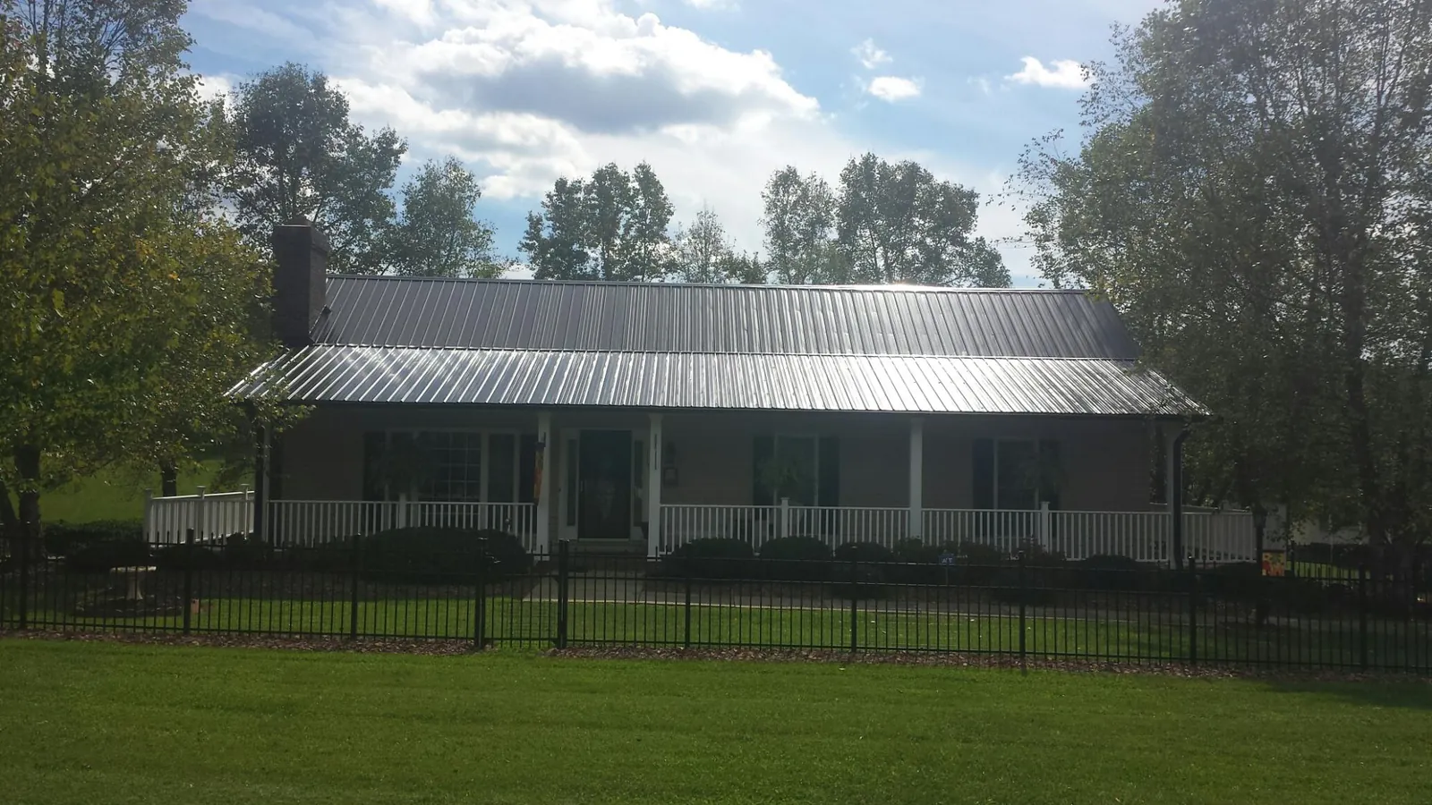 Gray metal roof on a brick ranch with a full width front porch — Gutter Guard Installation work by our crew in Dedham