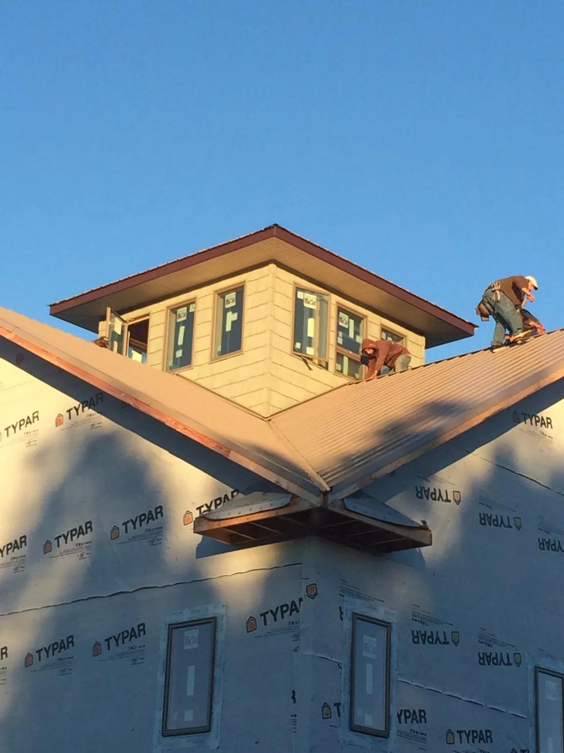 Roofers working around a rooftop cupola on a new metal roof at sunset — Roof Waterproofing in Dedham by Roofing Brothers